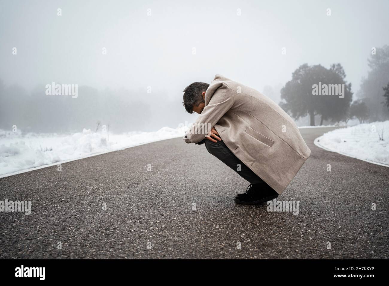 Einsamer Mann umarmt die Knie auf der Straße Stockfoto