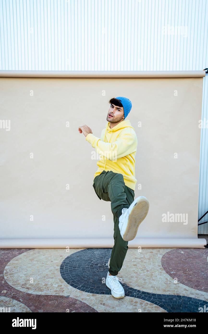 Junger männlicher Darsteller tanzt während er auf einem Bein nach dem Hintergrund balanciert Stockfoto