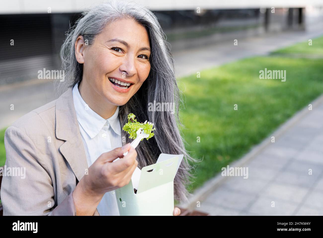 Lächelnde Frau mit grauem Haar, die die Lebensmittelbox hält Stockfoto