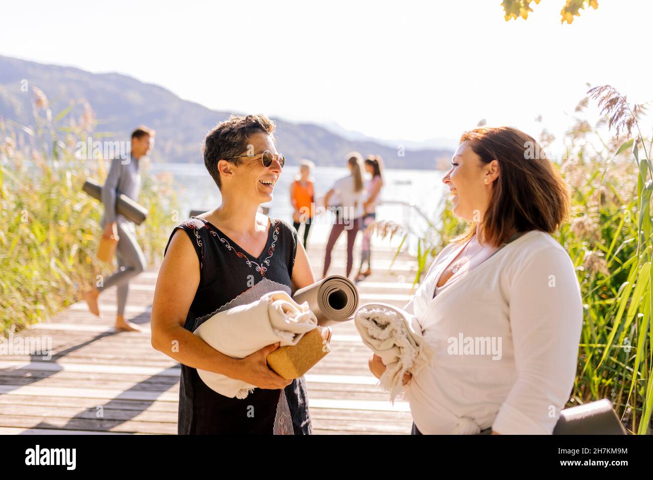 Frau mit Sonnenbrille im Gespräch mit einer Freundin beim Yoga-Kurs Stockfoto