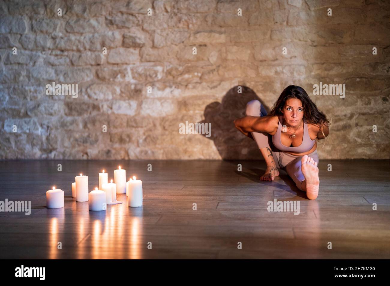 Reife Frau, die Marichyasana vor einer Steinmauer praktiziert Stockfoto