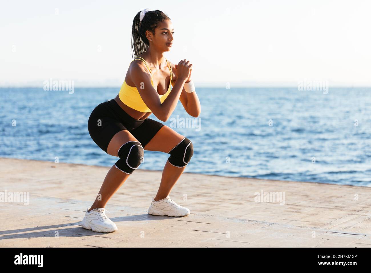 Junge weibliche Sportsperson tut Kniebeugen während sonnigen Tag Stockfoto