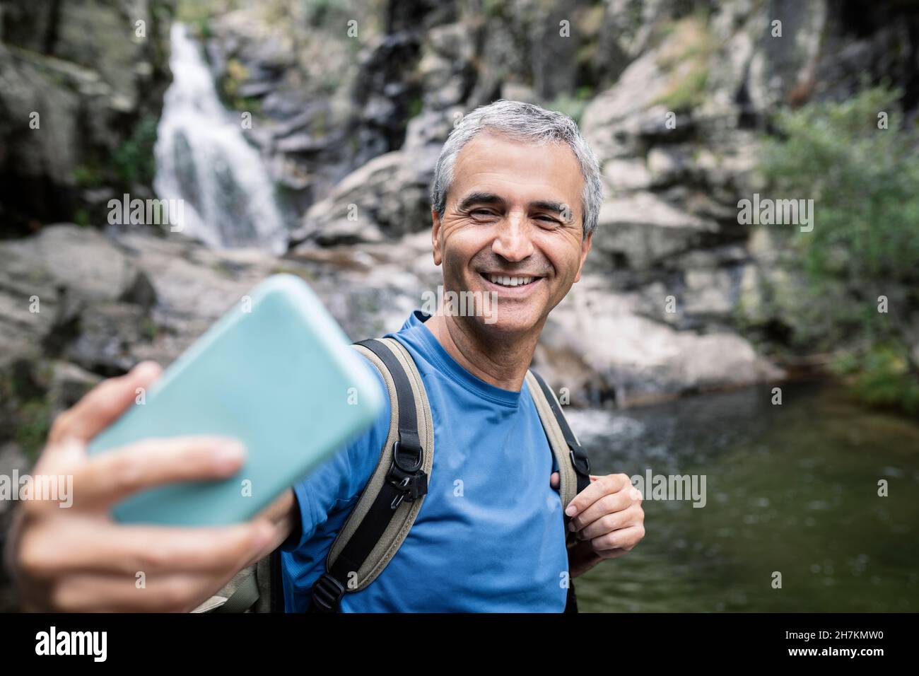 Reifer Mann lächelt im Wald während des Urlaubs Stockfoto