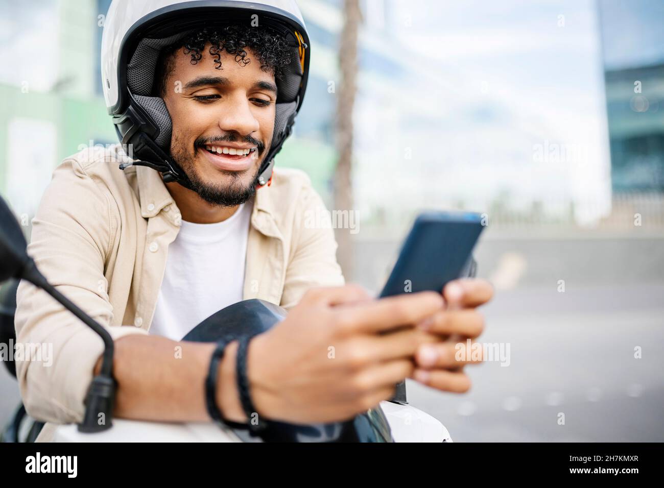 Lächelnder Mann mit Sturzhelm und Mobiltelefon Stockfoto
