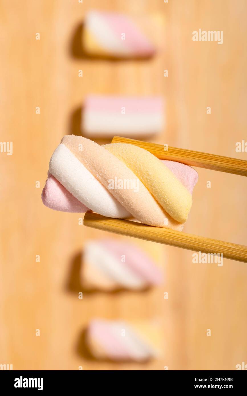Marshallows und Essstäbchen auf Holzbrett Stockfoto