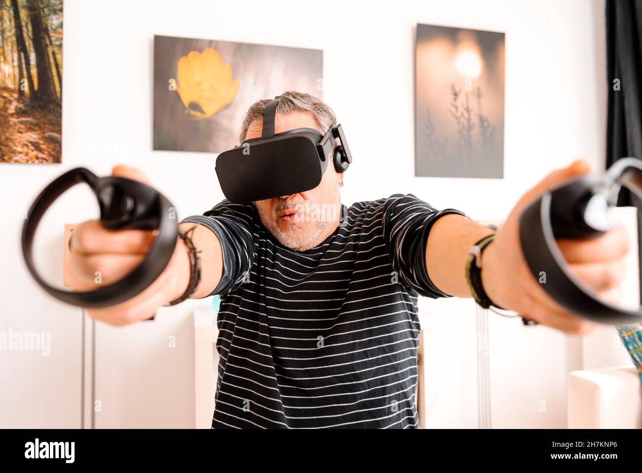Fröhlicher Mann mit erhobenen Armen trägt Virtual-Reality-Simulator zu Hause Stockfoto