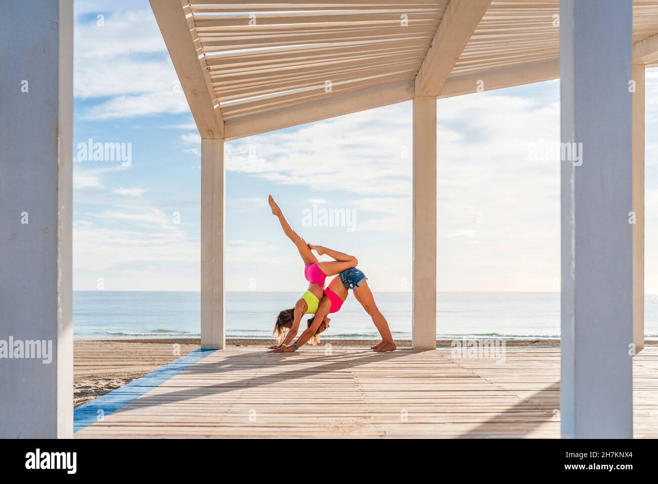 Weibliche Athleten machen Gymnastik am Strand Stockfoto