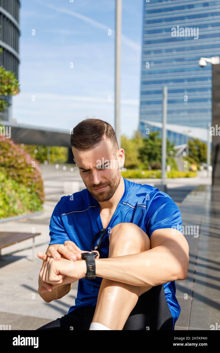 Lächelnde Sportlerin, die den Mann während eines sonnigen Tages beim Zeitabsehen ansieht Stockfoto