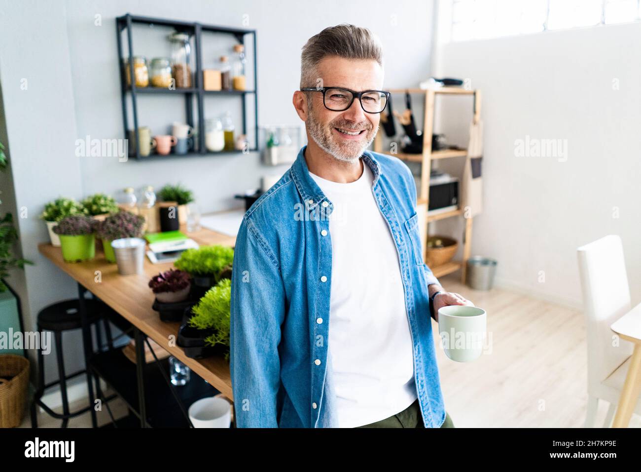 Mann mit der Hand in der Tasche hält die Kaffeetasse zu Hause Stockfoto