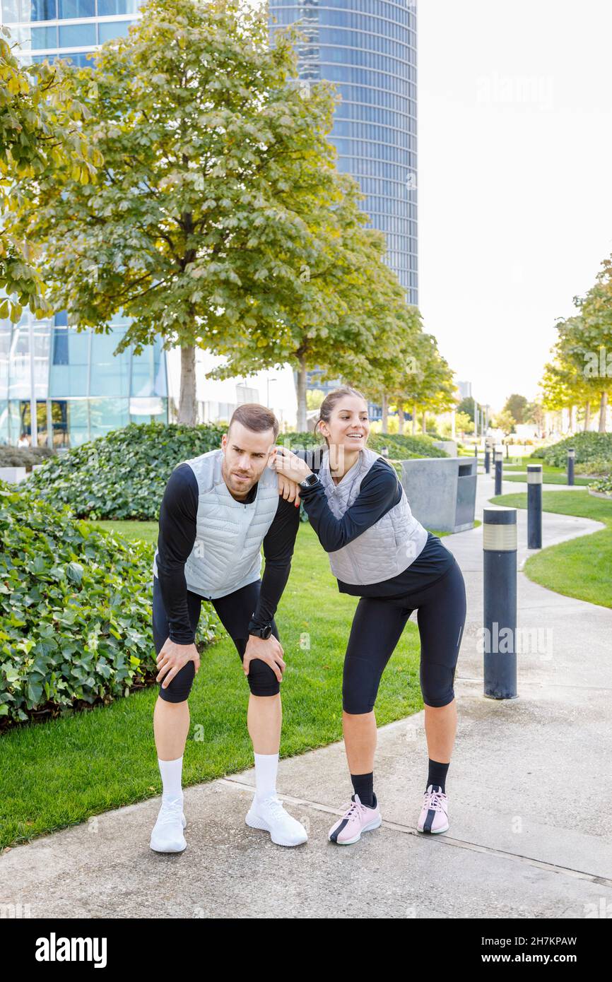 Müde männliche und weibliche Athleten im Park Stockfoto