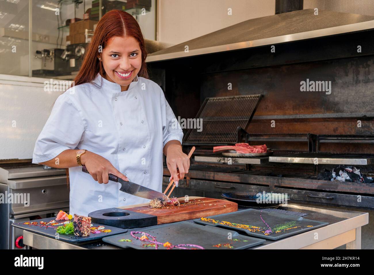 Lächelnde Köchin schneidet Essen im Restaurant Stockfoto