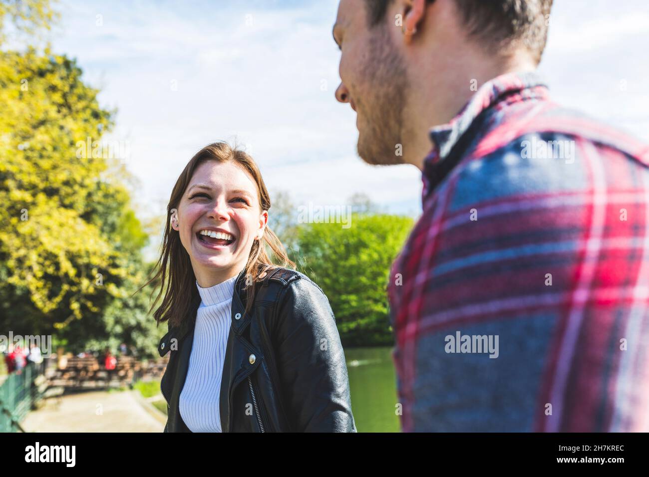 Glückliche Frau, die im Park mit einem Freund spricht Stockfoto