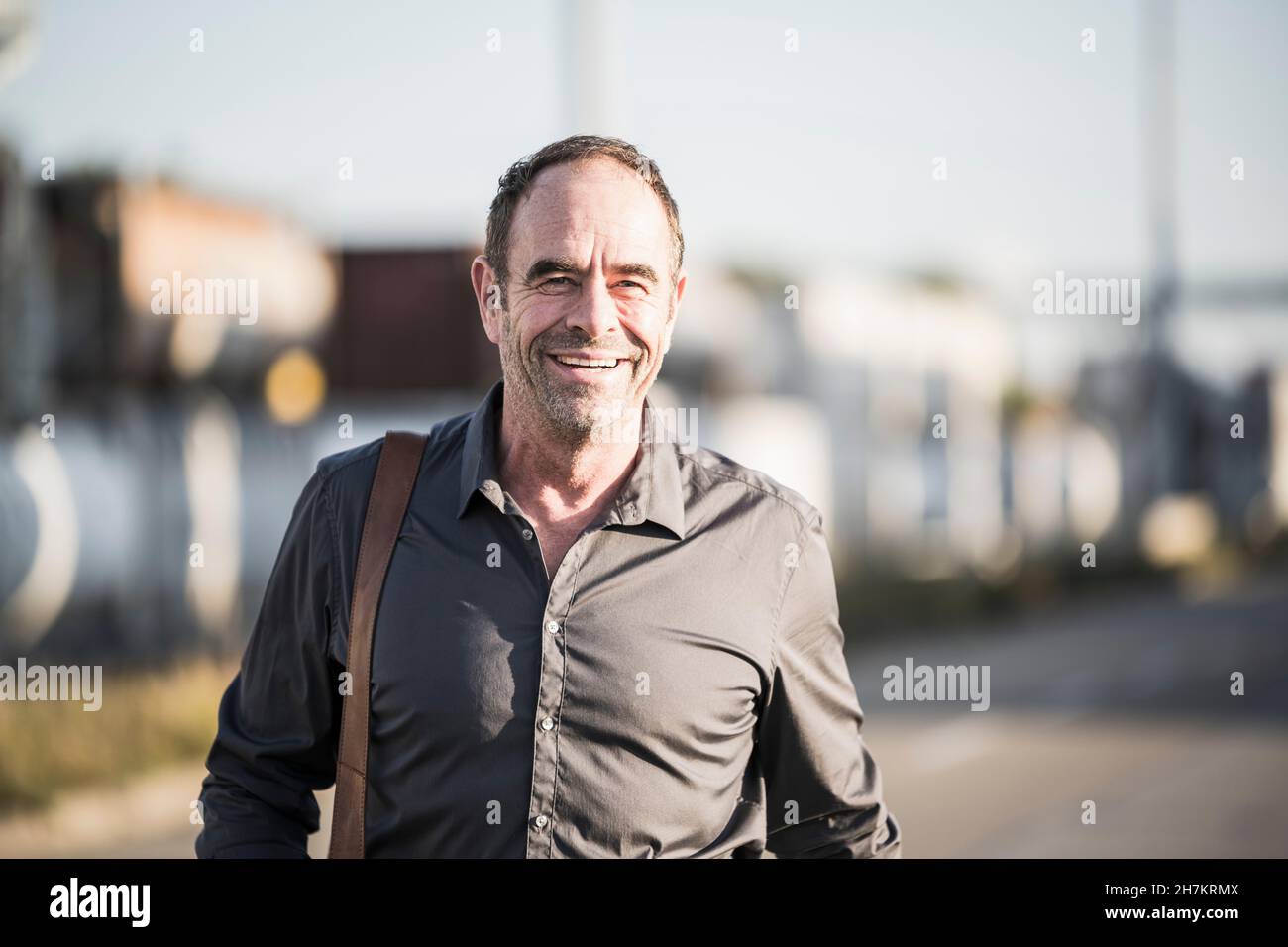 Fröhlicher Geschäftsmann mit grauem Hemd auf der Straße Stockfoto