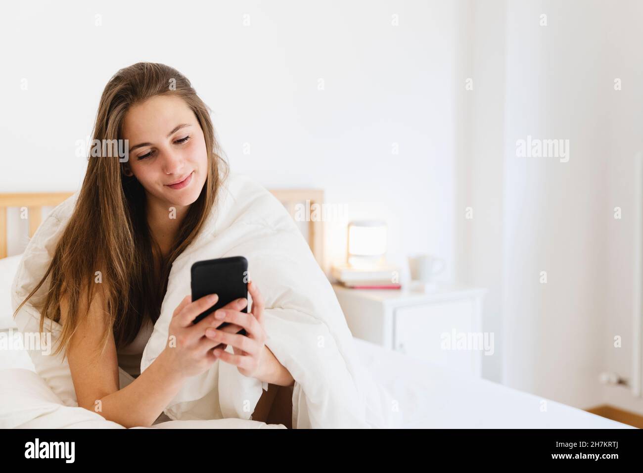 Lächelnde junge Frau mit braunem Haar im Smart-N-Bett Stockfoto