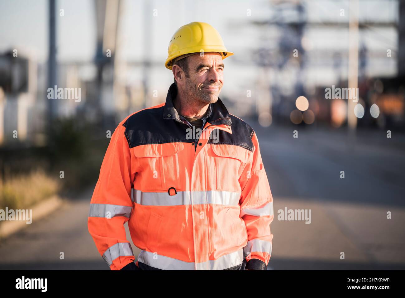 Männlicher Arbeiter mit reflektierender Jacke am kommerziellen Dock Stockfoto