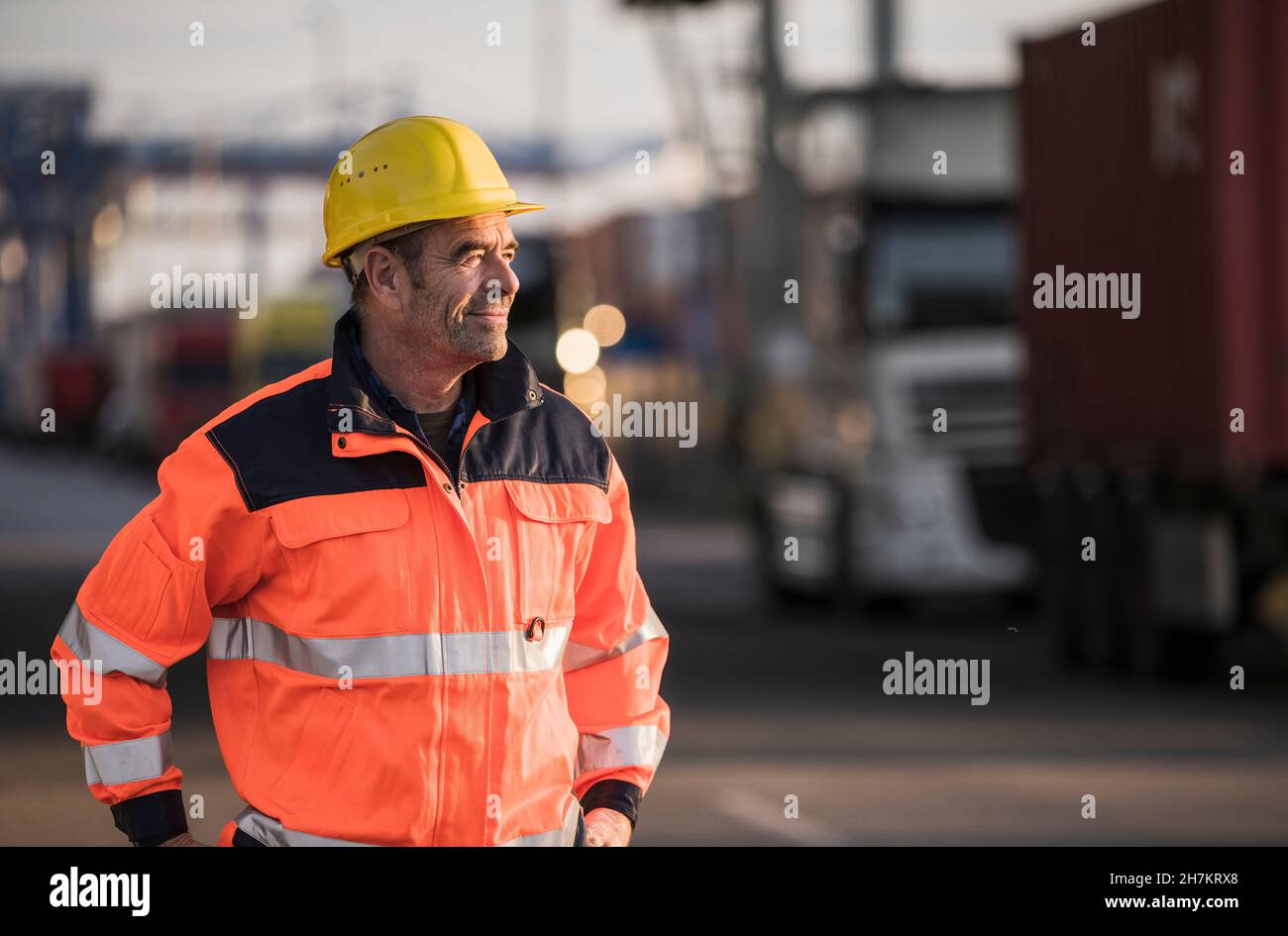 Lächelnder Arbeiter mit reflektierender Jacke in der Industrie Stockfoto