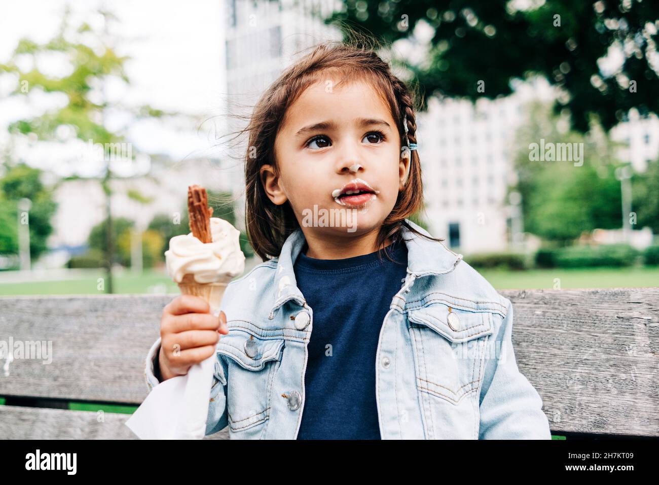 Nettes Mädchen mit braunen Haaren hält Eis-Kegel im Park Stockfoto