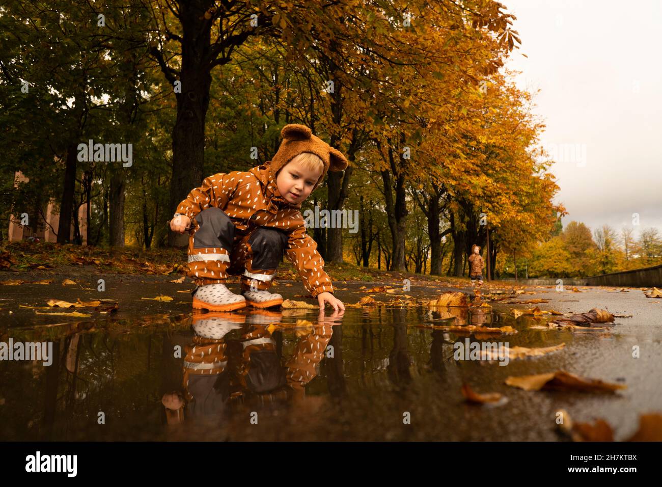 Junge spielt an der Pfütze im Herbstpark Stockfoto