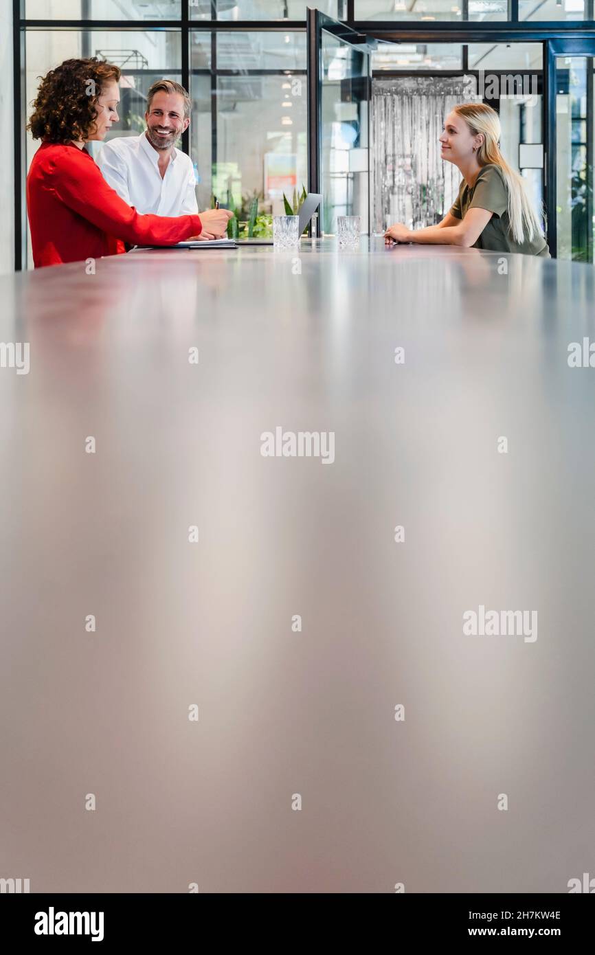 Rekrutierer, die ein Vorstellungsgespräch mit dem Kandidaten am Konferenztisch führen Stockfoto