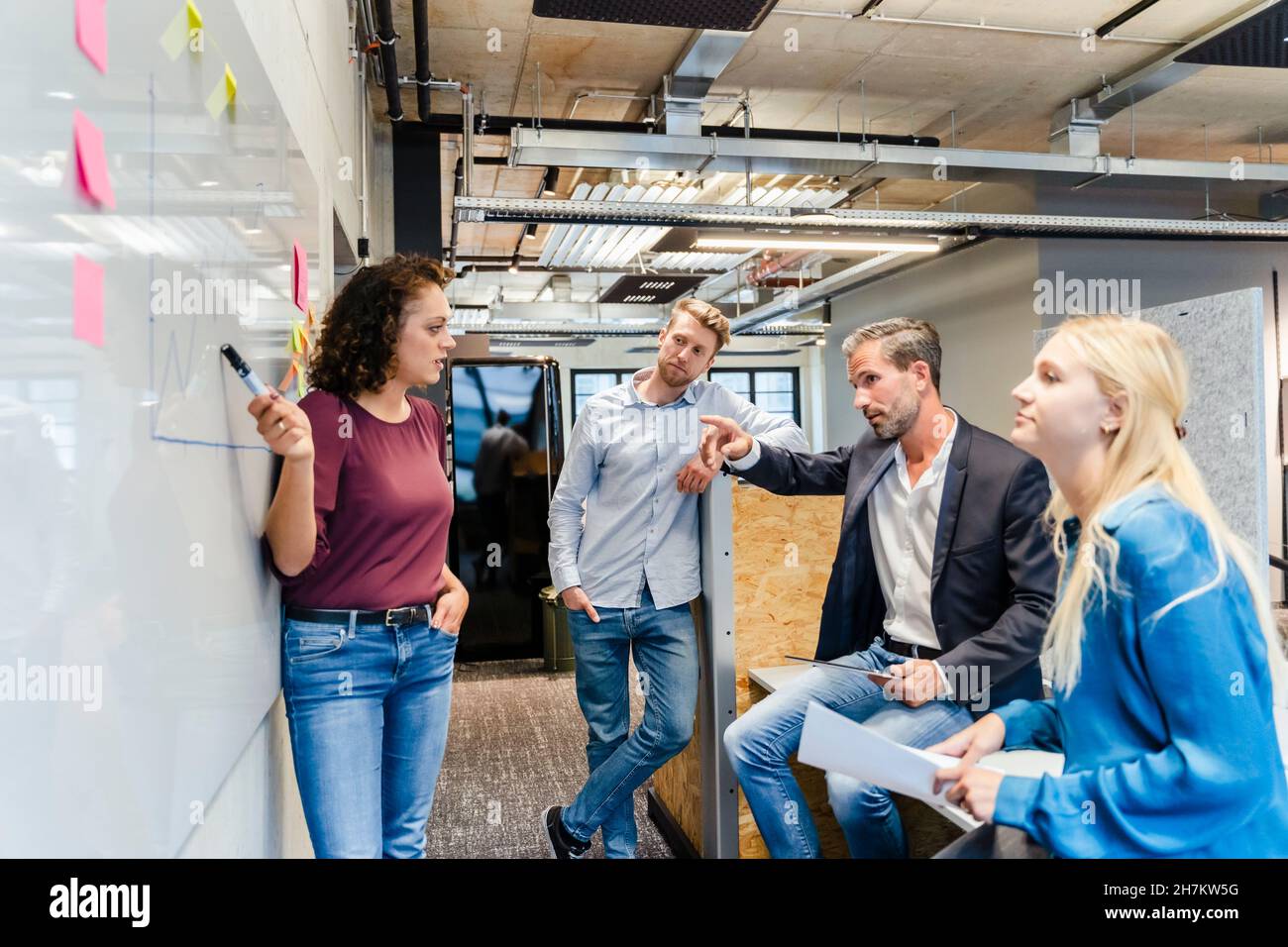 Geschäftsfrau, die Kollegen am Whiteboard vorführt Stockfoto