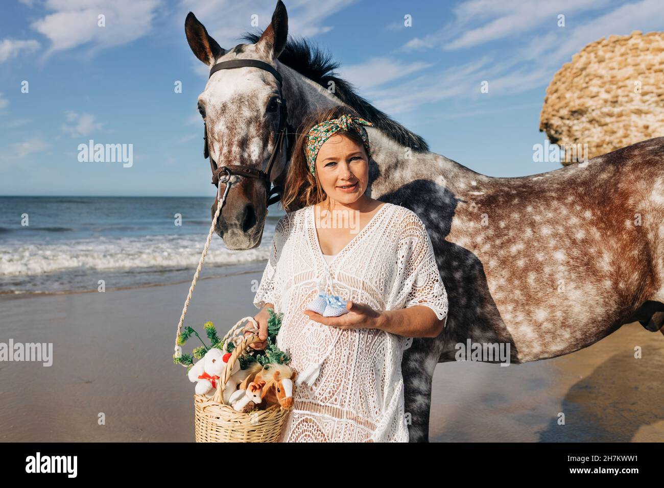 Schwanger Mutter mit Baby Booties stehen zu Pferd am Strand Stockfoto