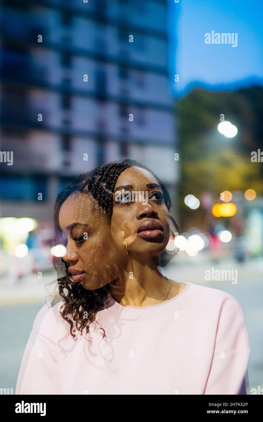 Doppelbelichtung einer jungen Frau mit geflochtenen Haaren in der Stadt Stockfoto