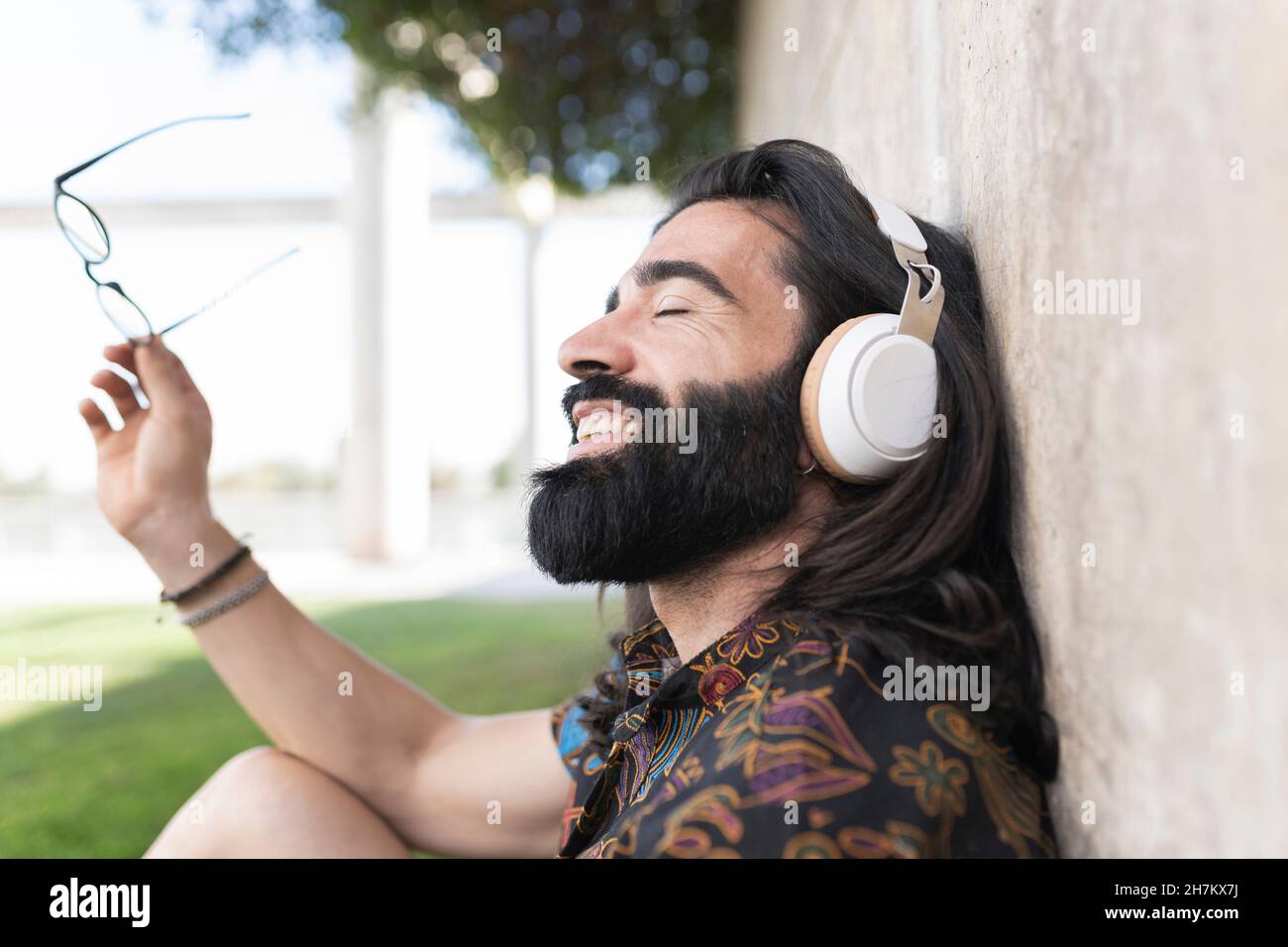 Bärtiger Mann mit geschlossenen Augen, der im öffentlichen Park Musik hört Stockfoto