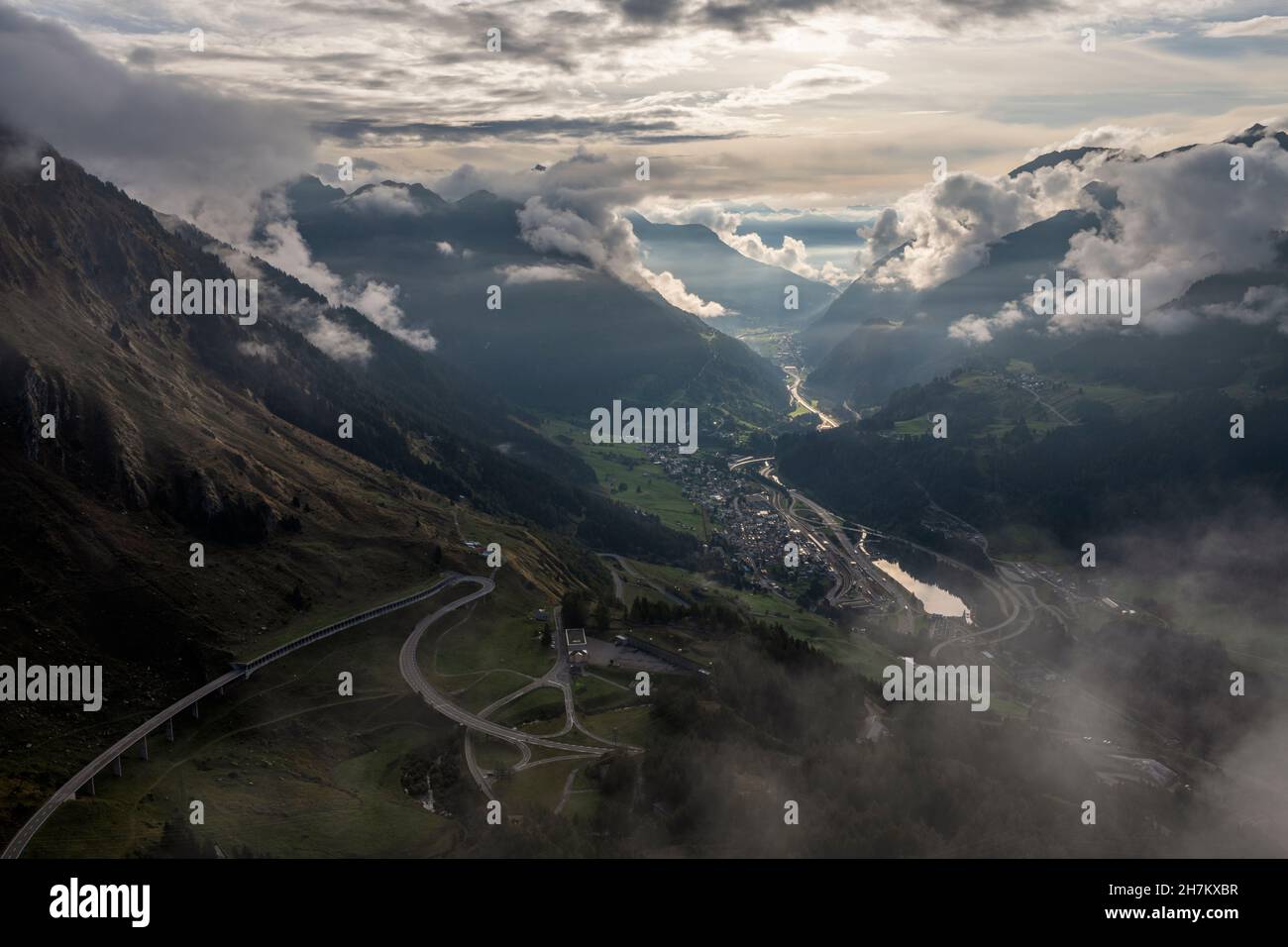 Schweiz, Tessin, Airolo, dramatische Sicht auf Gotthard Pass und Bergdorf bei Dämmerung Stockfoto