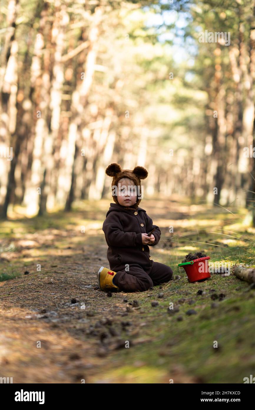 Nettes Mädchen kniet von Eimer spielen auf Gehweg im Wald Stockfoto