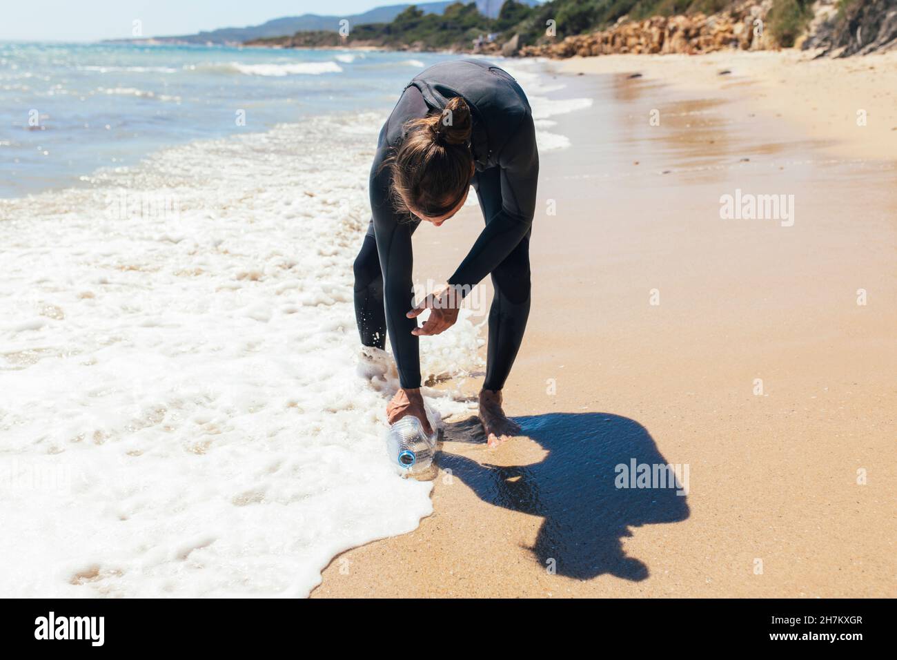 Männlicher Freiwilliger pflückt Plastikflasche am Strand Stockfoto