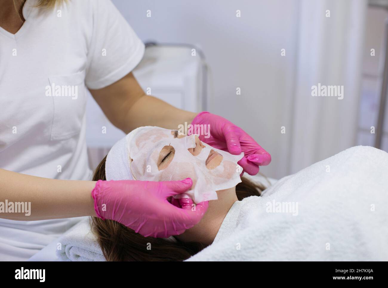 Kosmetikerin Anwendung feuchtigkeitsspendende Gesichtsmaske auf Frau im Salon Stockfoto