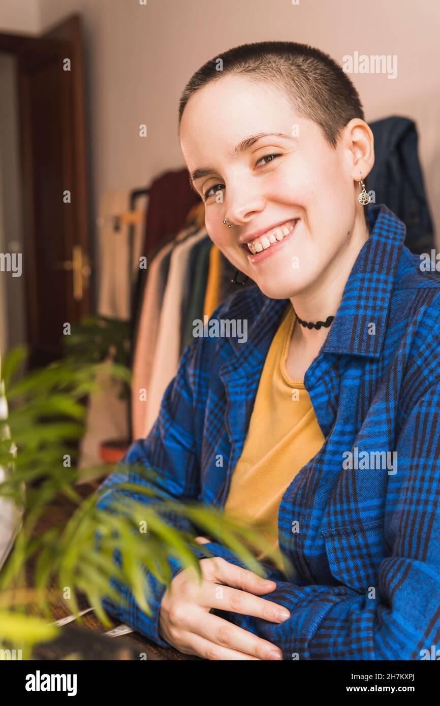 Lächelnde Schneiderin mit rasierten Haaren in der Werkstatt Stockfoto