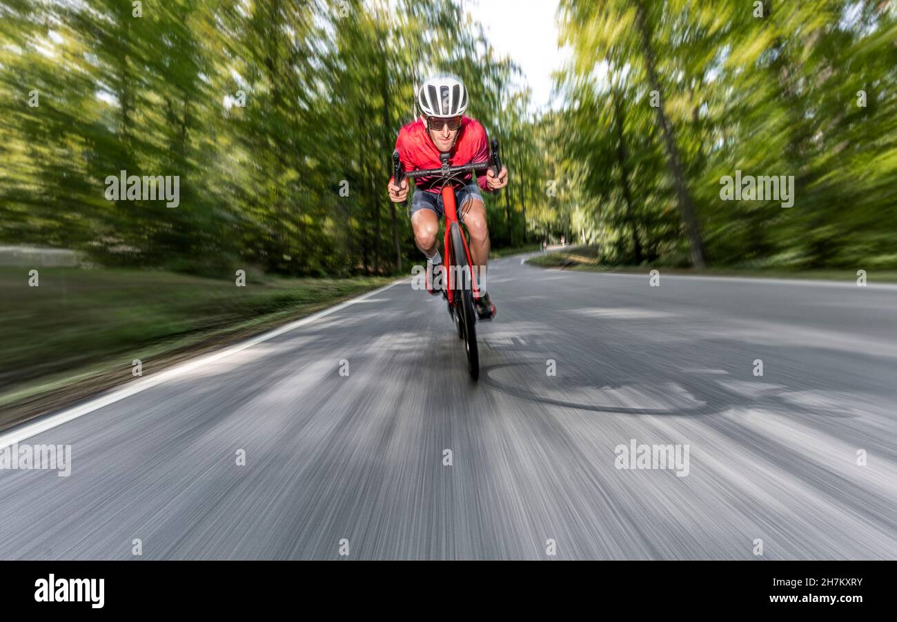 Männlicher Radfahrer, der auf einer asphaltierten Forststraße unterwegs ist Stockfoto