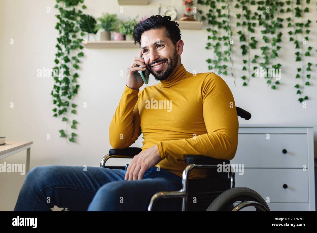 Lächelnder, behinderter Mann, der im Rollstuhl ein Buch liest Stockfoto