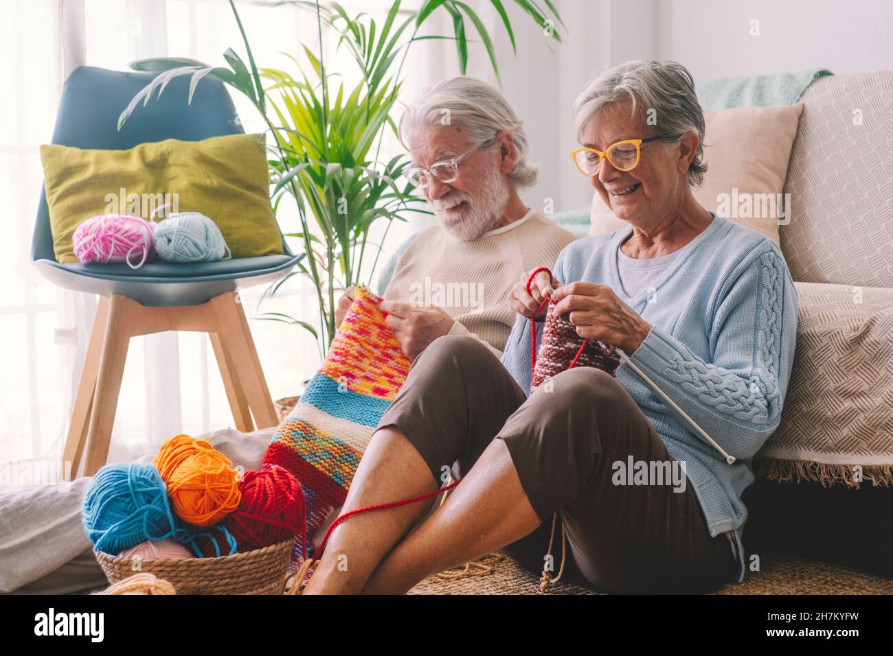 Seniorenpaar strickt Wolle im Wohnzimmer Stockfoto