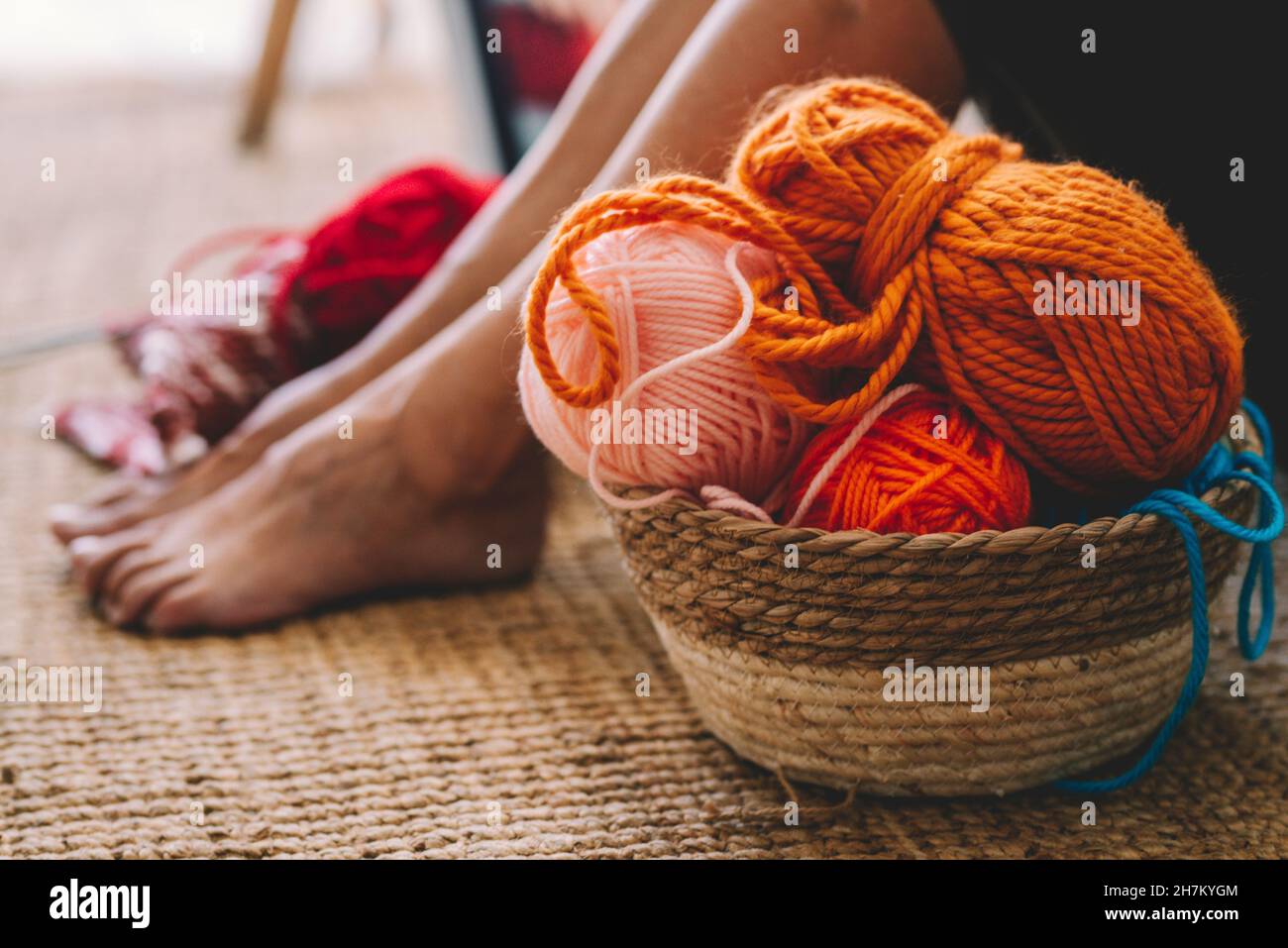 Frau sitzt am Korb mit Wollkugeln im Wohnzimmer Stockfoto