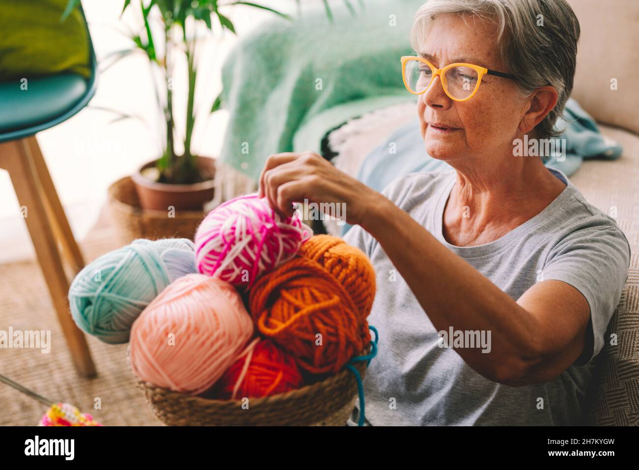 Frau, die zu Hause einen Wollball aus dem Korb wählt Stockfoto