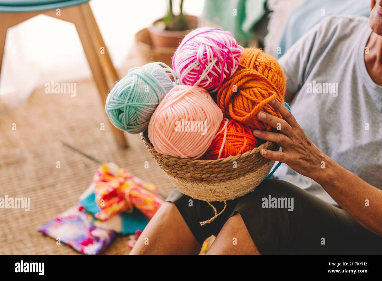 Frau, die einen Korb mit Wollkugeln im Wohnzimmer hält Stockfoto