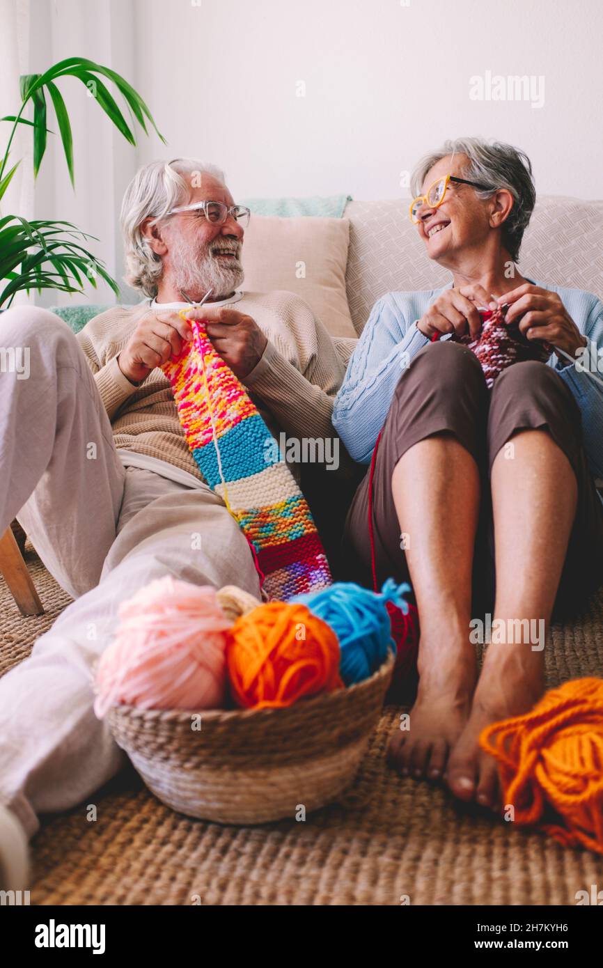 Lächelndes Seniorenpaar strickt Wolle im Wohnzimmer Stockfoto