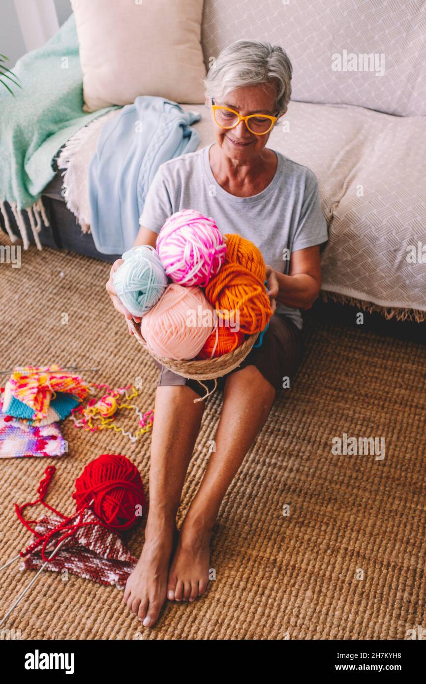 Frau mit Korb aus Wollkugeln im Wohnzimmer sitzen Stockfoto