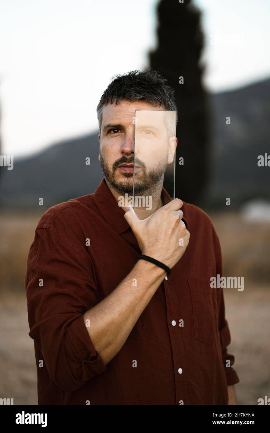 Mann schaut durch transparentes Glasstück Stockfoto