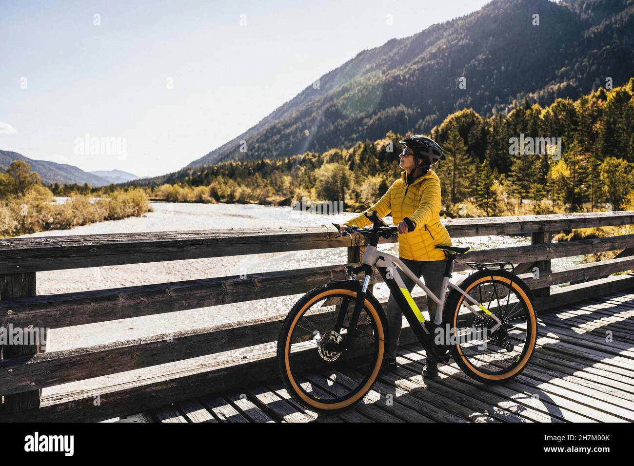 Frau mit Fahrrad auf einer Brücke mit Blick auf die Berge Stockfoto