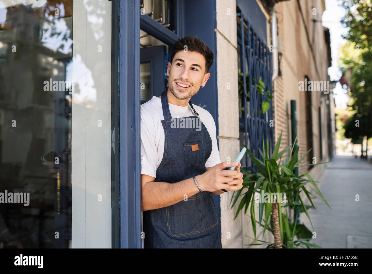 Lächelnder Besitzer winkt Hand am Eingang des Cafés Stockfoto