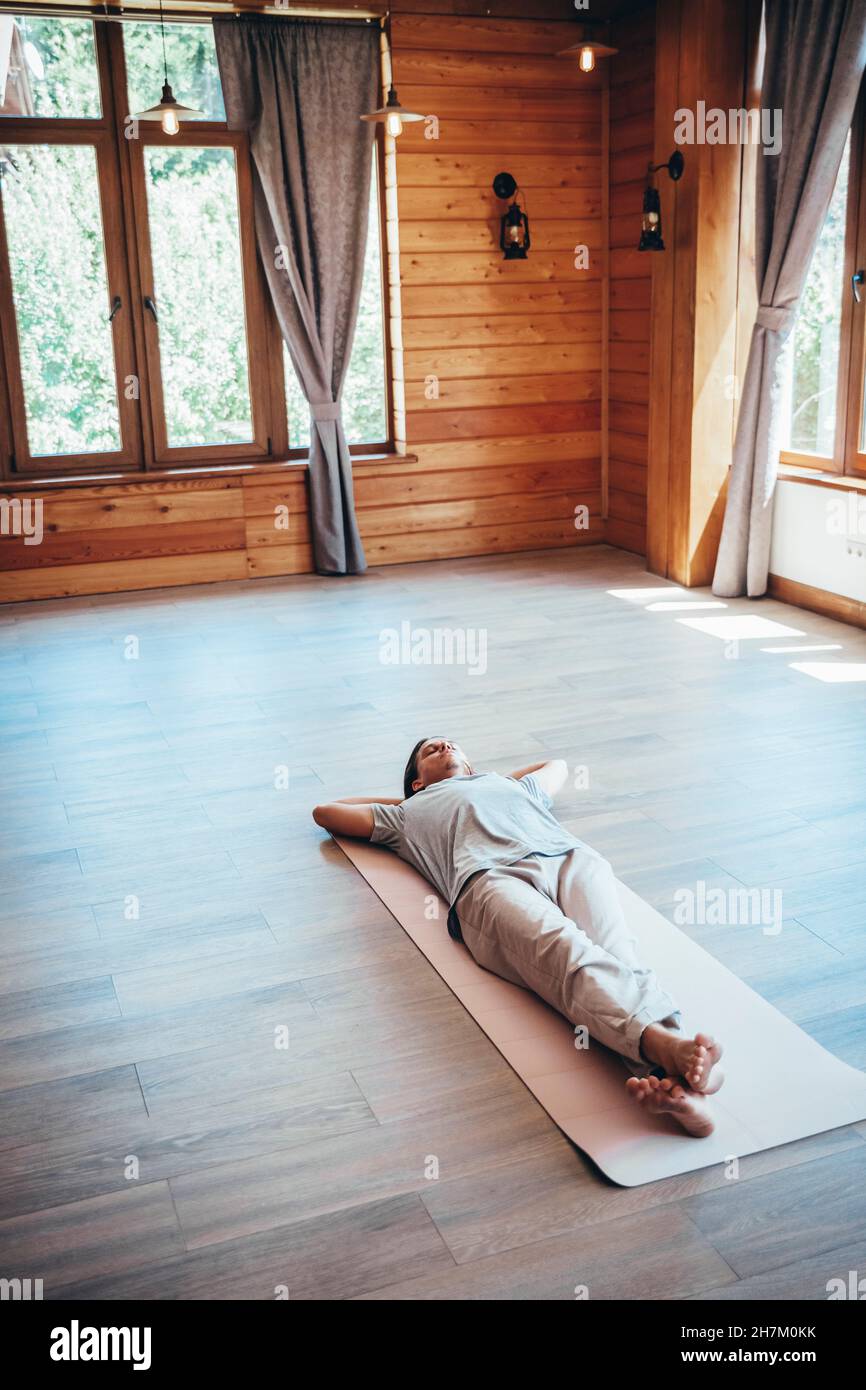 Mann, der sich auf der Yogamatte im Wellness-Center entspannt Stockfoto
