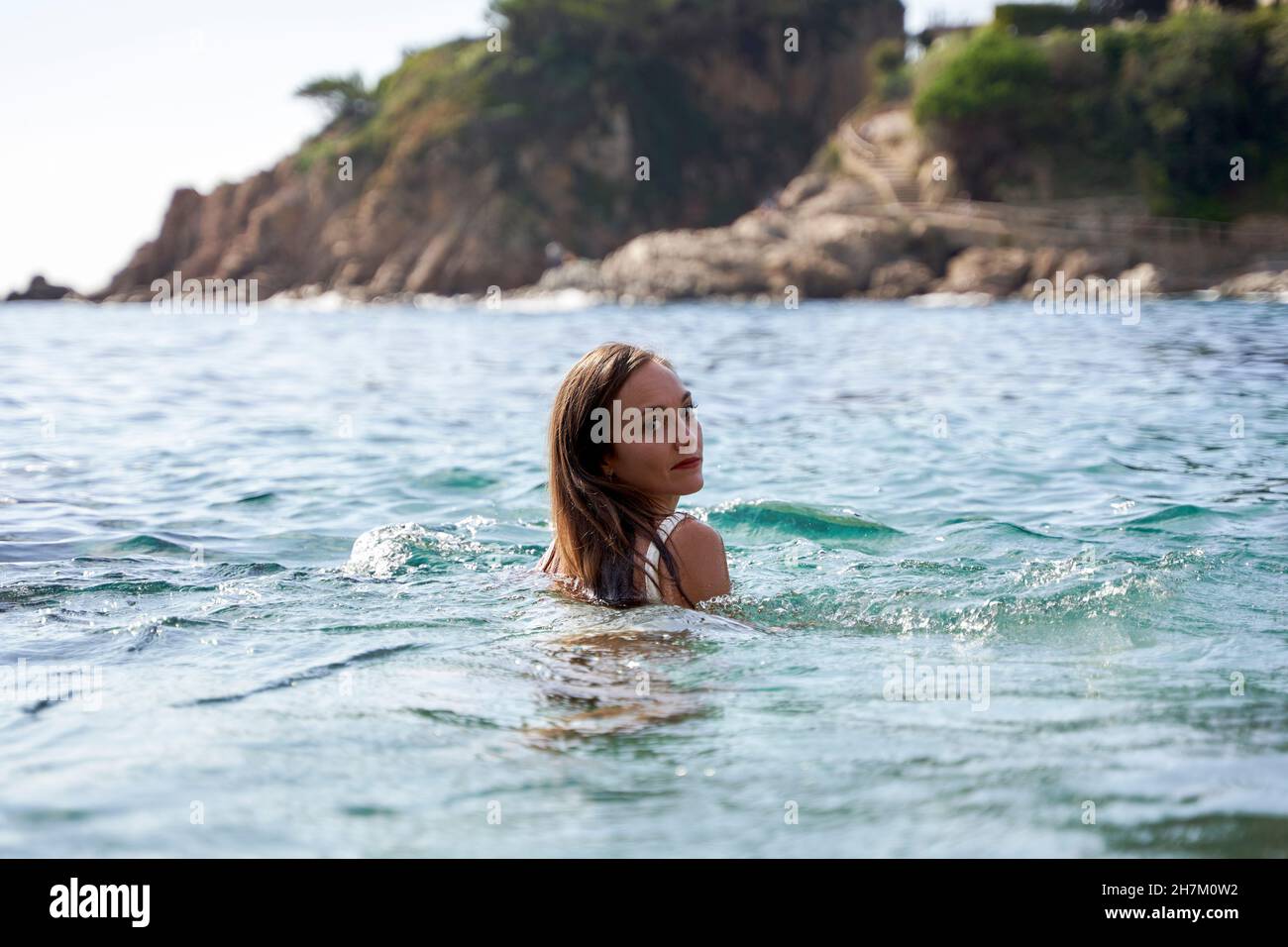 Junge Frau, die im Meer über die Schulter schaut Stockfoto