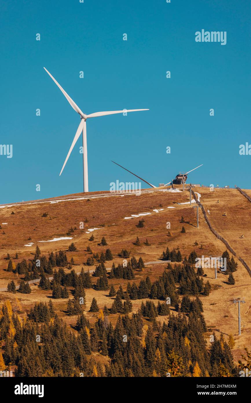 Brauner Herbstbergrücken mit Windturbine, die im Hintergrund vor dem klaren blauen Himmel steht Stockfoto