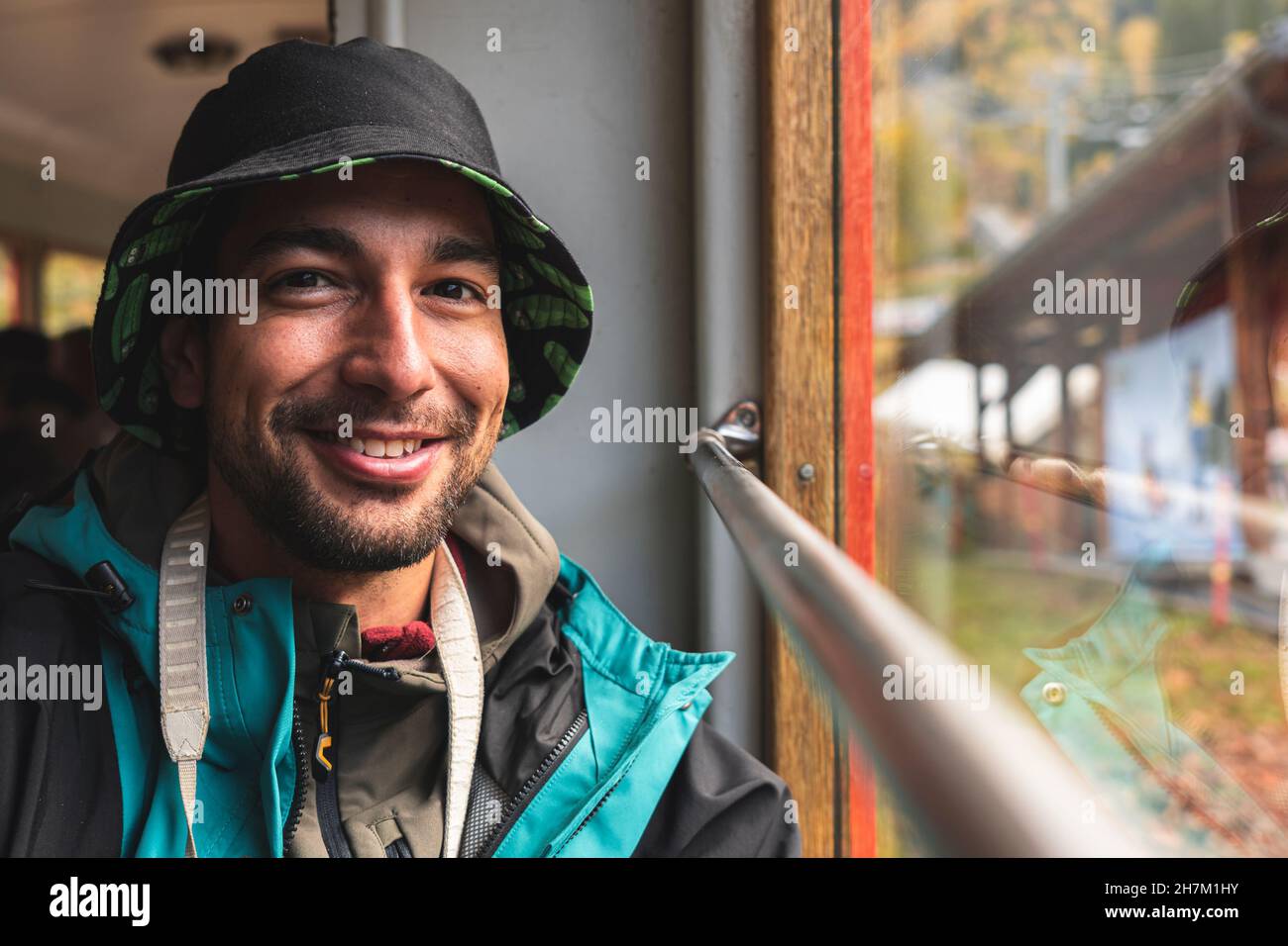 Fröhlicher Mann im Urlaub, der durch das Zugfenster schaute Stockfoto