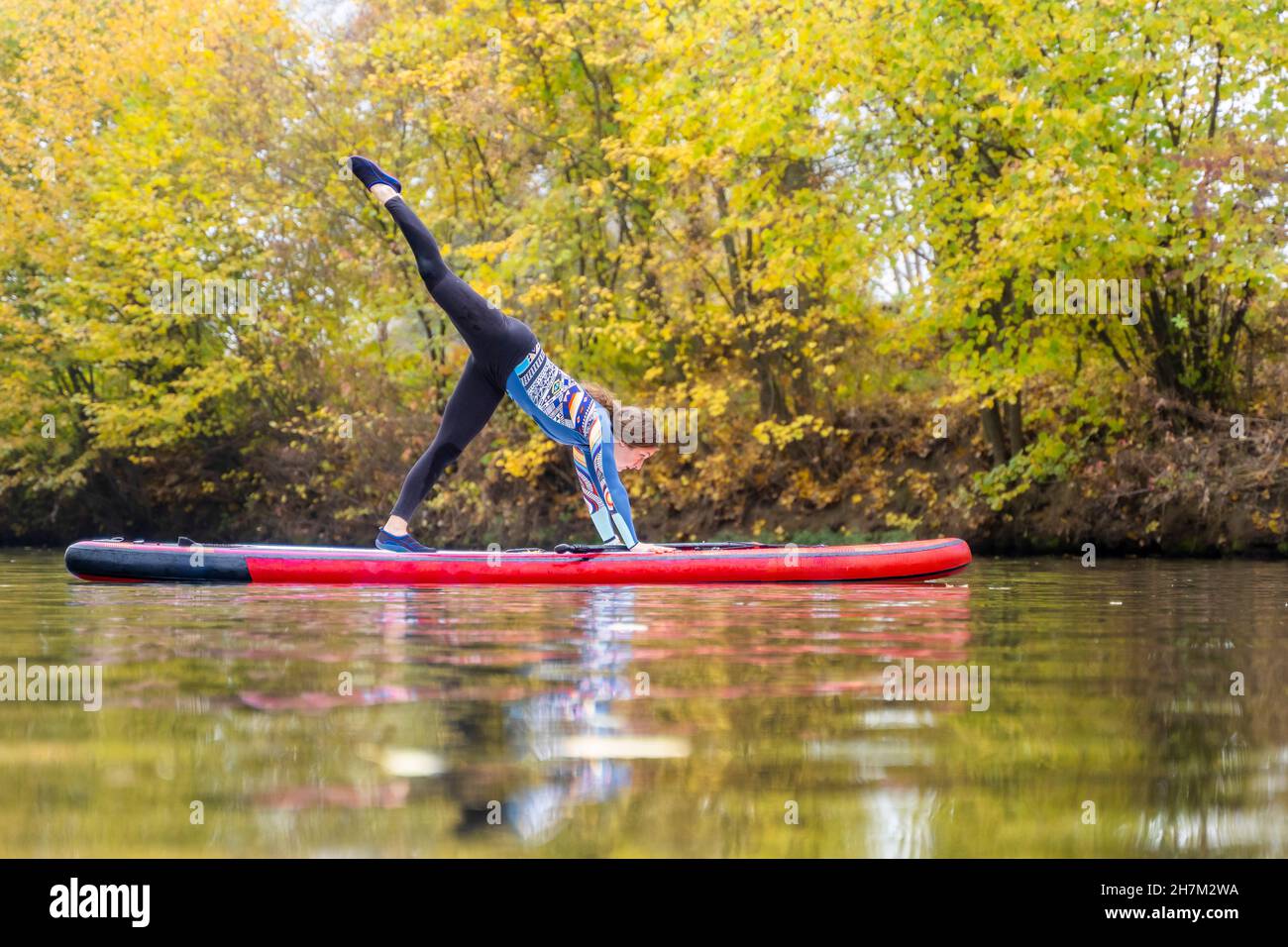 Sportlerin, die am Rems Fluss, Baden-Württemberg, Yoga auf dem Paddleboard praktiziert Stockfoto