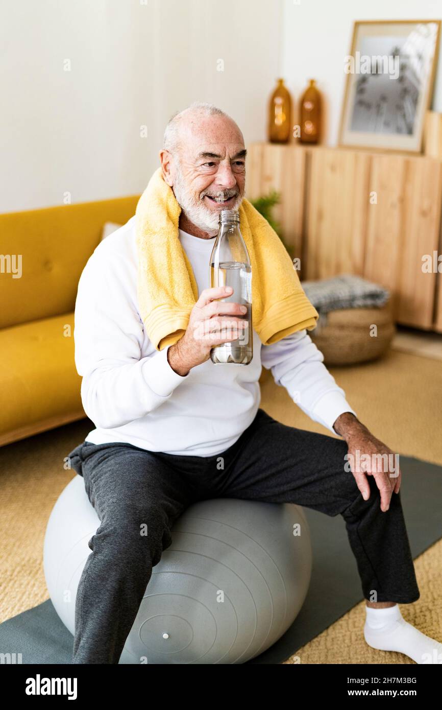 Aktiver älterer Mann, der zu Hause auf dem Fitnessball trainiert Stockfoto