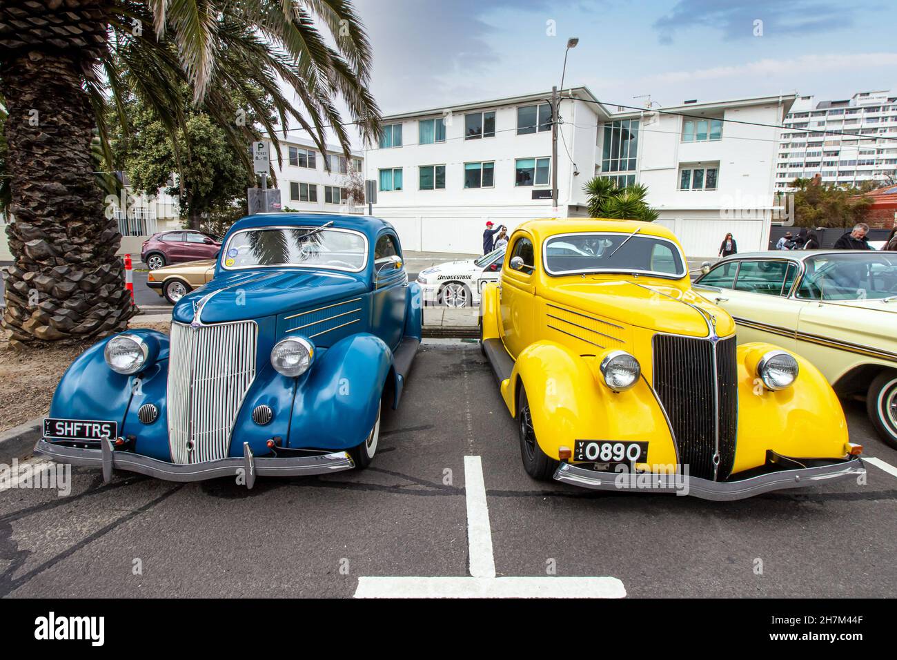 Zwei Oldtimer parkten nebeneinander in einer Straße. Ford Modell 48, 1936. Gelb und blau. Bunte, klassische Automobile. Stockfoto